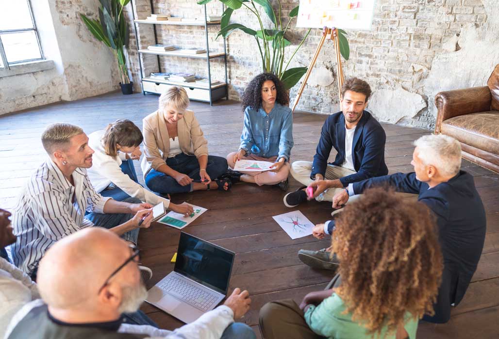 Multiracial business team is gathered in a circle on the floor,