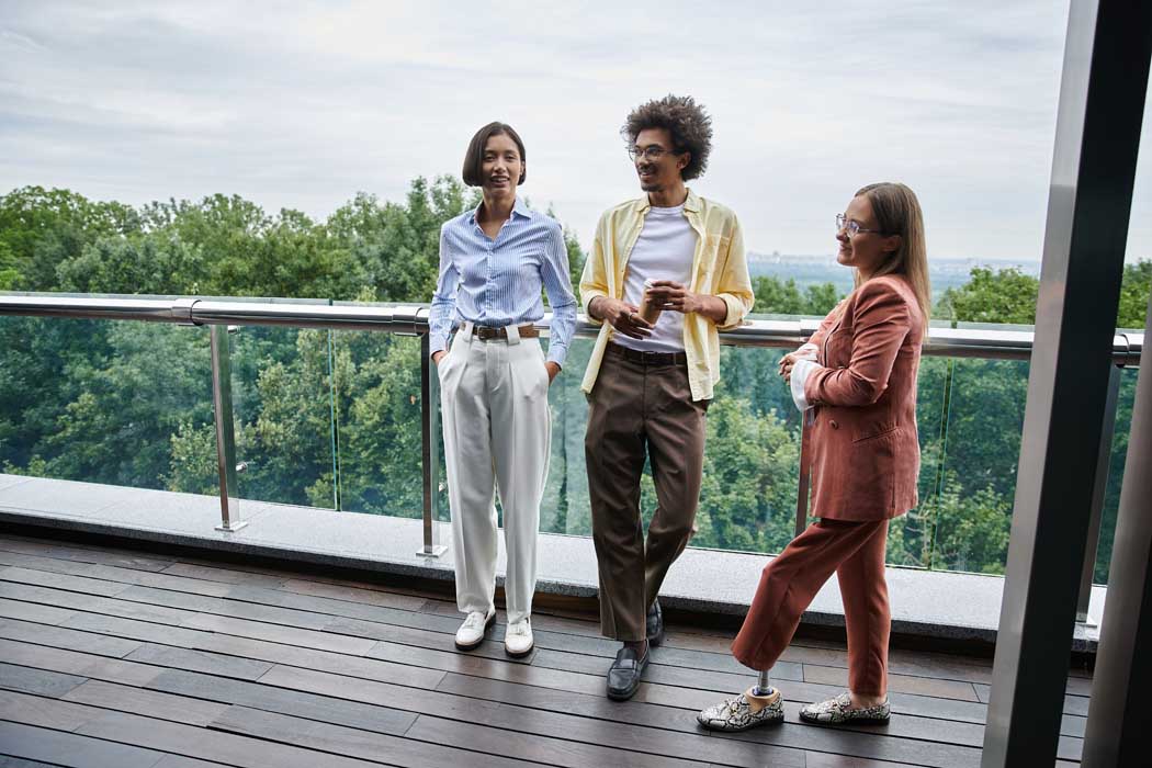 Three colleagues chat on a rooftop terrace, enjoying a break in