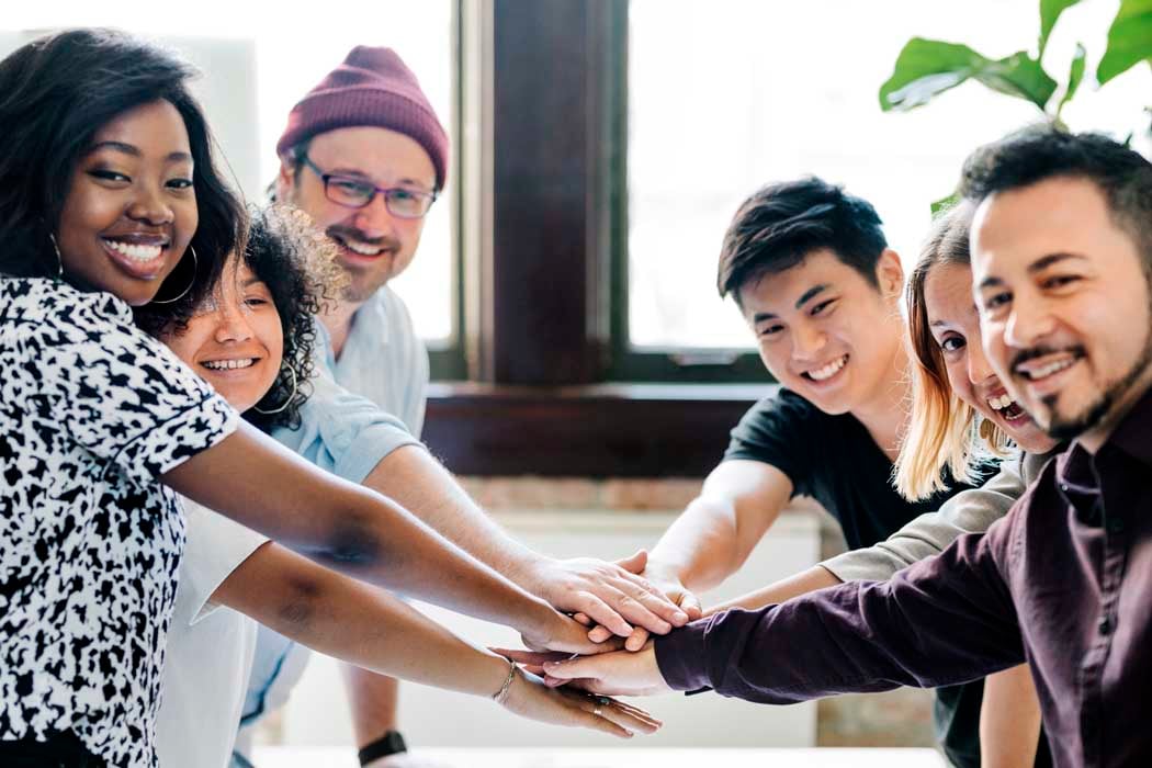 Happy team putting their hands together for success
